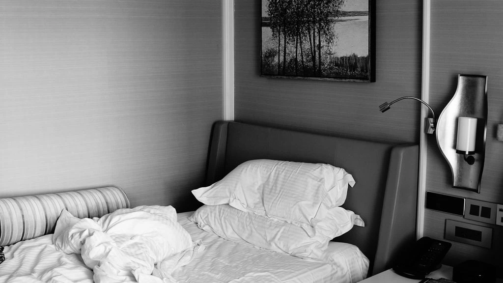 Praxis Hotels in-room collateral — cream and burnt-orange paper goods on a linen bedspread.